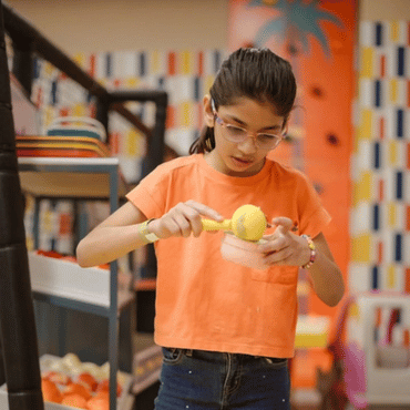 Girl enjoying a hands-on creative activity at an indoor kids play area.