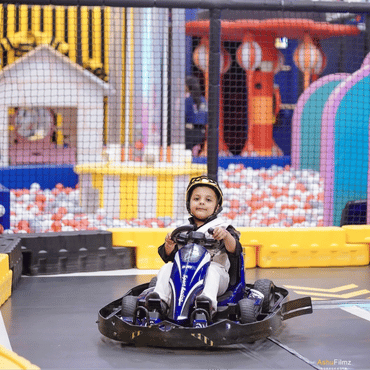 Child enjoying a go-kart ride at an indoor kids play area.